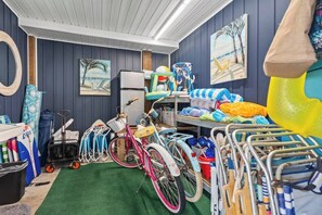 Une chambre avec un lit superposé, un vélo, une planche de surf et divers équipements de sport.