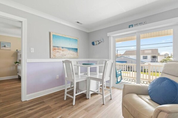 Une pièce comprenant une table à manger et des chaises, un tableau accroché au mur et une vue sur l’extérieur.