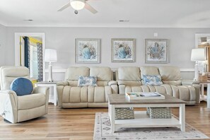 A living room with a sofa set, a coffee table, and artwork on the wall.