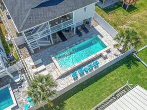 Une maison à deux étages dotée d’une piscine, d’un espace extérieur aménagé pour s’asseoir et d’une terrasse clôturée.