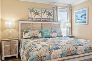 Une chambre à coucher comprenant un lit, deux tables de chevet, une tête de lit et des œuvres d’art murales.
