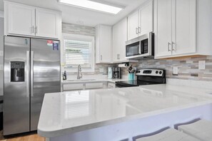 Une cuisine moderne avec des armoires blanches, des appareils en acier inoxydable et un grand îlot central.