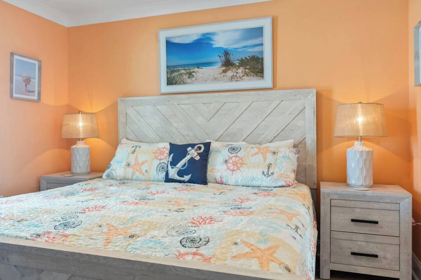 Un dormitorio con cama, dos mesitas de noche, cabecera y un cuadro en la pared.
