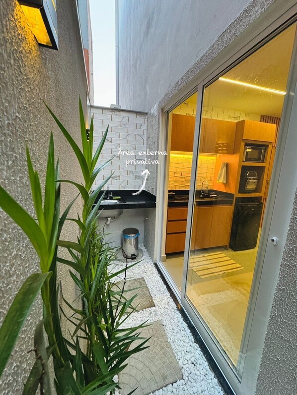 A modern kitchen with a sliding glass door leading to a dining area. - Flat Pé na Areia Iriri (Anchieta)