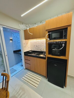 A modern kitchen with wooden cabinets, a built-in microwave, and a compact dishwasher. - Flat Pé na Areia Iriri (Anchieta)