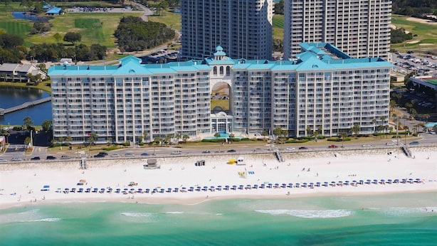 Een groot hotel met een centrale binnenplaats, meerdere verdiepingen en een ligging aan het strand.