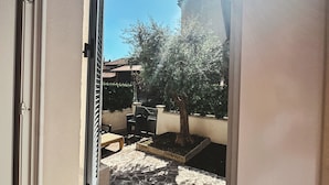 A balcony with a view of a courtyard, a potted tree, and a stone floor. - Casa da Victoria - Apartment 1 (Castrezzato)