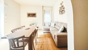 A dining area with a wooden table and chairs, a sofa, and a painting on the wall. - Casa da Victoria - Apartment 1 (Castrezzato)
