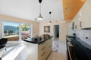 A modern kitchen with a black countertop, white cabinets, and pendant lighting.