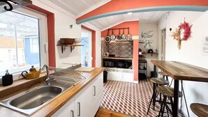 A compact kitchen with a sink, stove, and bar stools. - Charming Apartment with River Views & Sunny Terraces near Lisbon (Vila Franca de Xira)