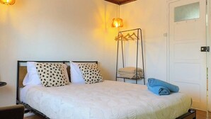 A bedroom with a wooden ceiling, a bed with white bedding, two hanging lamps, and a white door. - Charming Apartment with River Views & Sunny Terraces near Lisbon (Vila Franca de Xira)