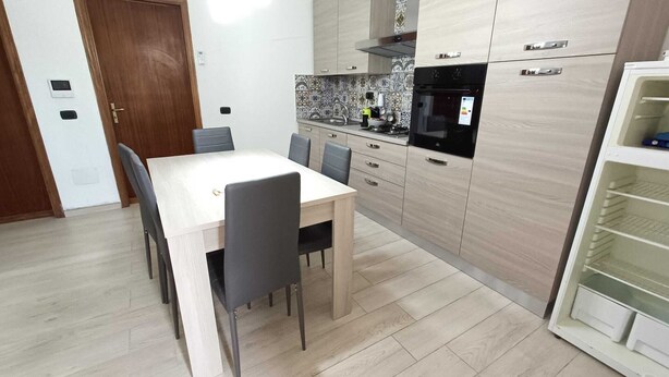 Una cocina moderna con una mesa de comedor, sillas y electrodomésticos integrados.