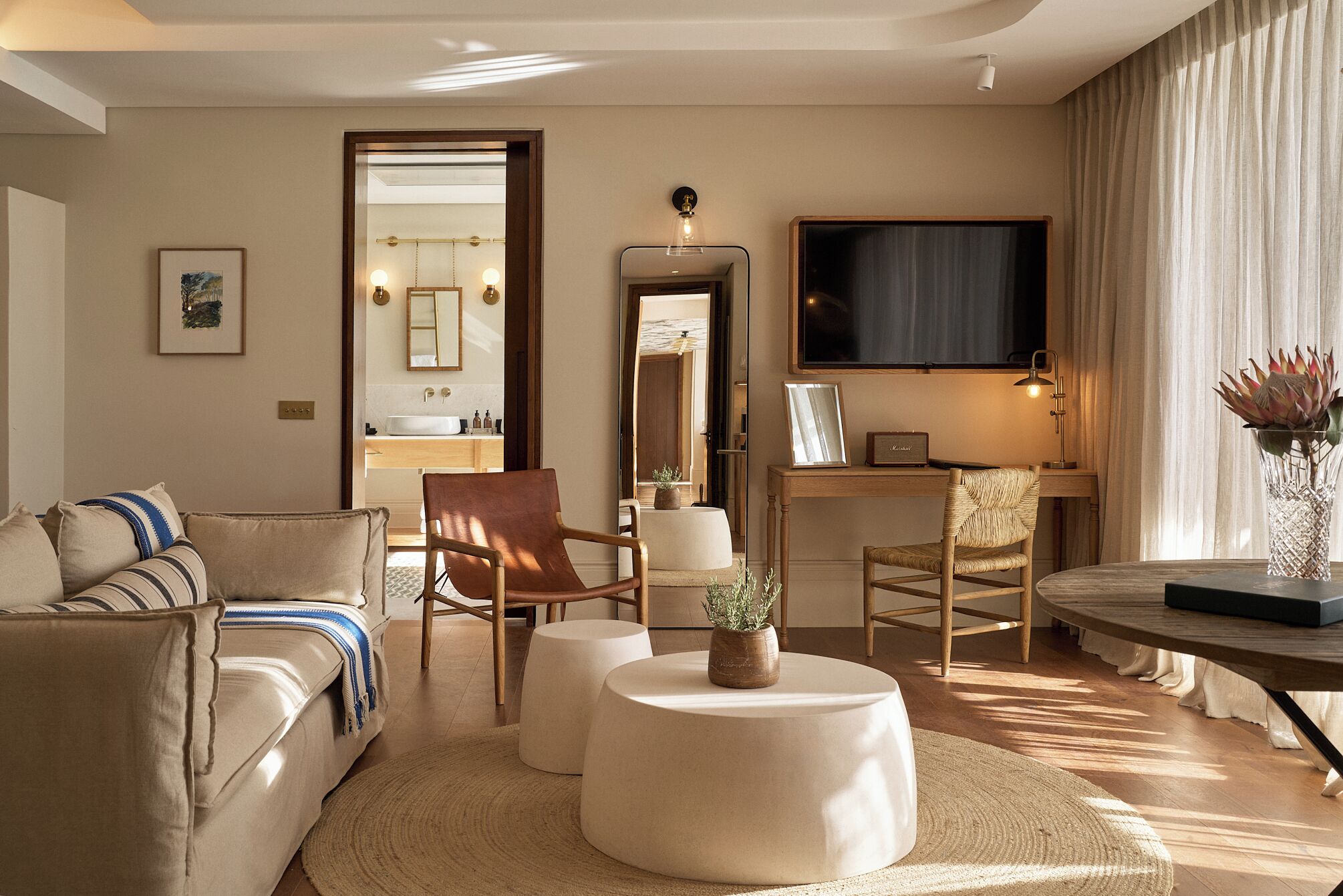 A modern living room with a sofa, armchairs, a coffee table, and a television.