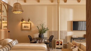 A cozy room with a bed, a table with chairs, a fireplace, and a television. - The Alexander Estate (Cape Town)