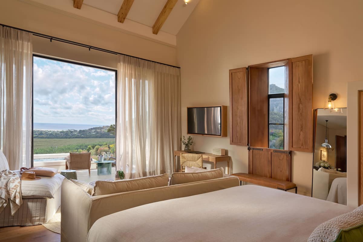 A spacious bedroom with a large bed, a desk, and a view of the countryside.