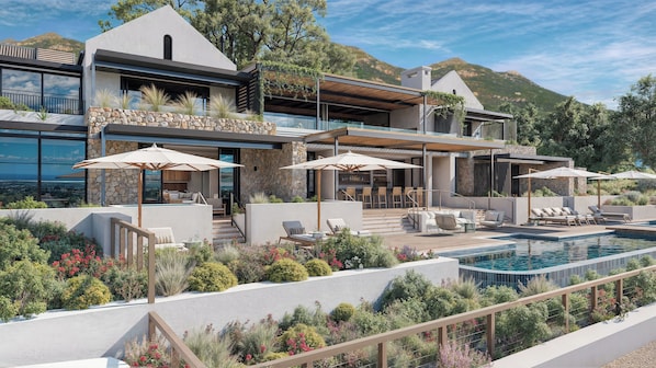A modern house with a pool, outdoor seating, and a view of the mountains.
