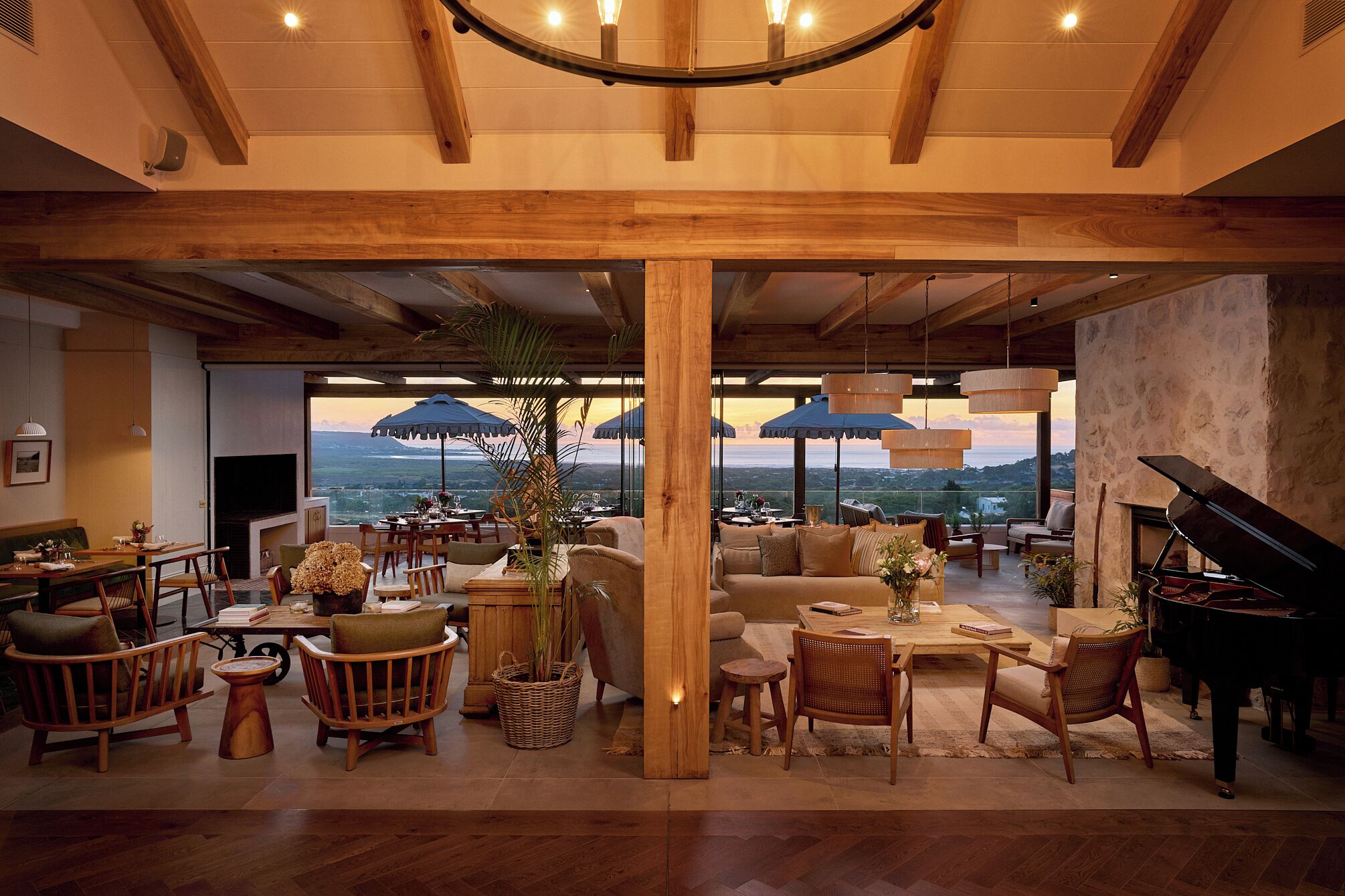 A spacious living area with a grand piano, comfortable seating, and a view of the landscape.