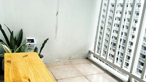 A balcony with a wooden bench, potted plants, and a view of a high-rise building. - Crizzy's Hub Crizel @ Shore Residences with Balcony + Amenity View (Pasay City)