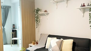 A modern living room with a black leather sofa, white coffee table, and decorative items on shelves. - Crizzy's Hub Crizel @ Shore Residences with Balcony + Amenity View (Pasay City)
