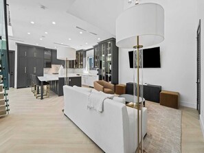 Una cocina moderna con armarios oscuros, una encimera blanca y una zona de comedor con mesa y sillas.