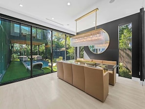 Un interior moderno con pared de vidrio, piscina y zona de comedor.