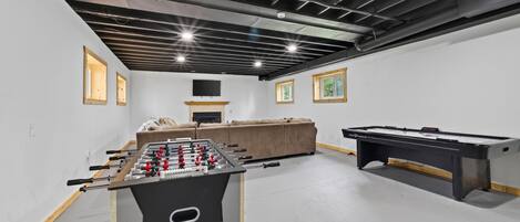 Une pièce équipée d’un baby-foot, d’une table de billard et d’un canapé.