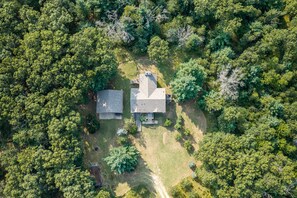 An aerial view of a property with two buildings, surrounded by dense forest.