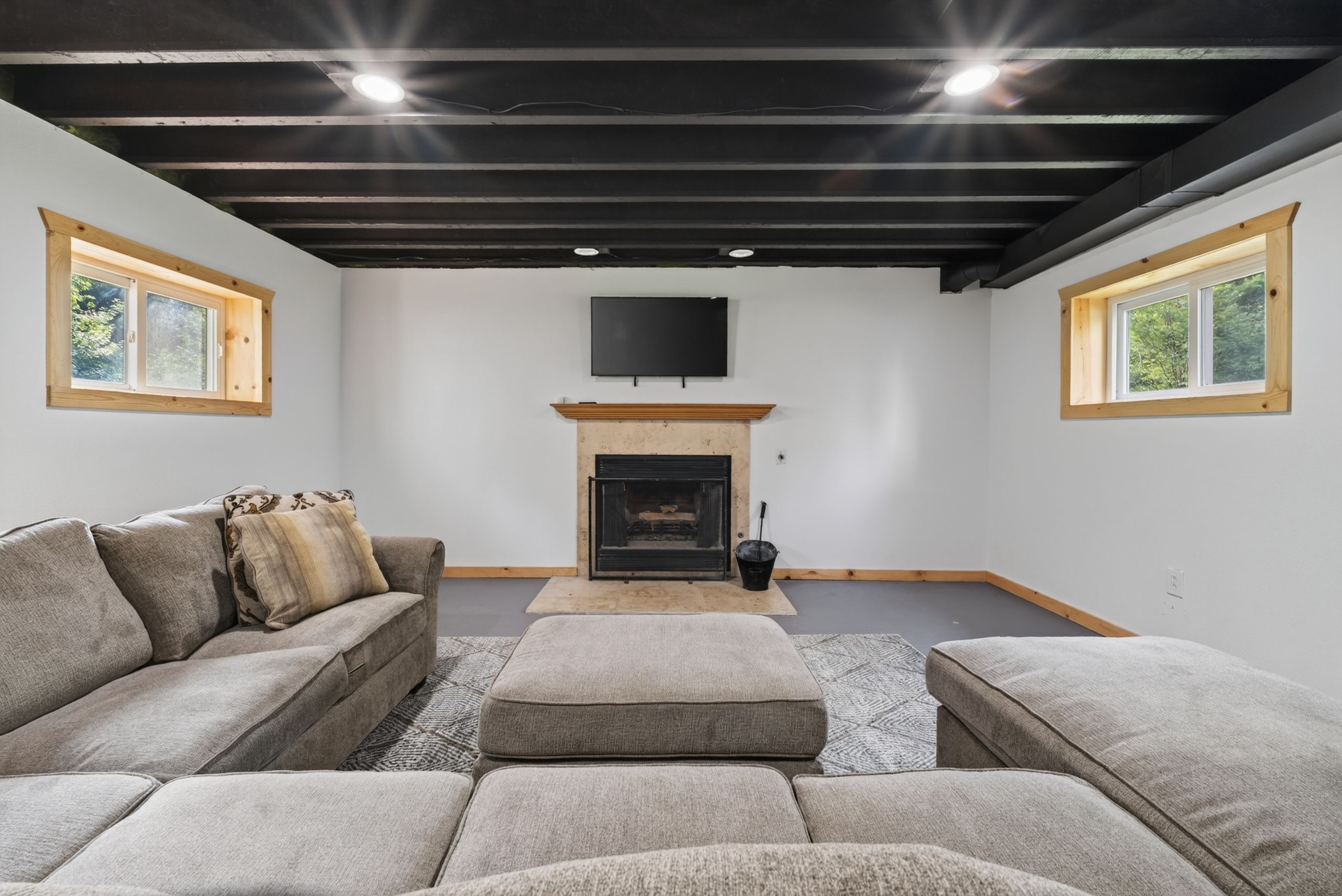 A modern living room with a fireplace, a sofa, and a television mounted on the wall.