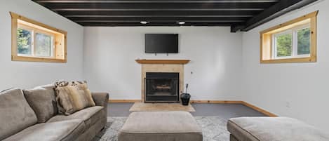 A modern living room with a fireplace, a sofa, and a television mounted on the wall.