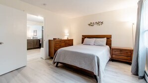 Une chambre à coucher comprenant un lit, des tables de chevet, une commode et un luminaire fixé au mur.