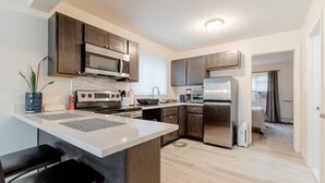 Une cuisine moderne avec des meubles en bois foncé, des appareils électroménagers en acier inoxydable et un îlot central.