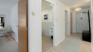 Un intérieur moderne avec une porte en bois, des murs blancs, un lavabo blanc et un tapis à motifs.
