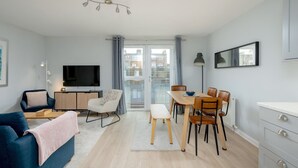 Un salon moderne comprenant un canapé, un téléviseur, une table à manger et des chaises.