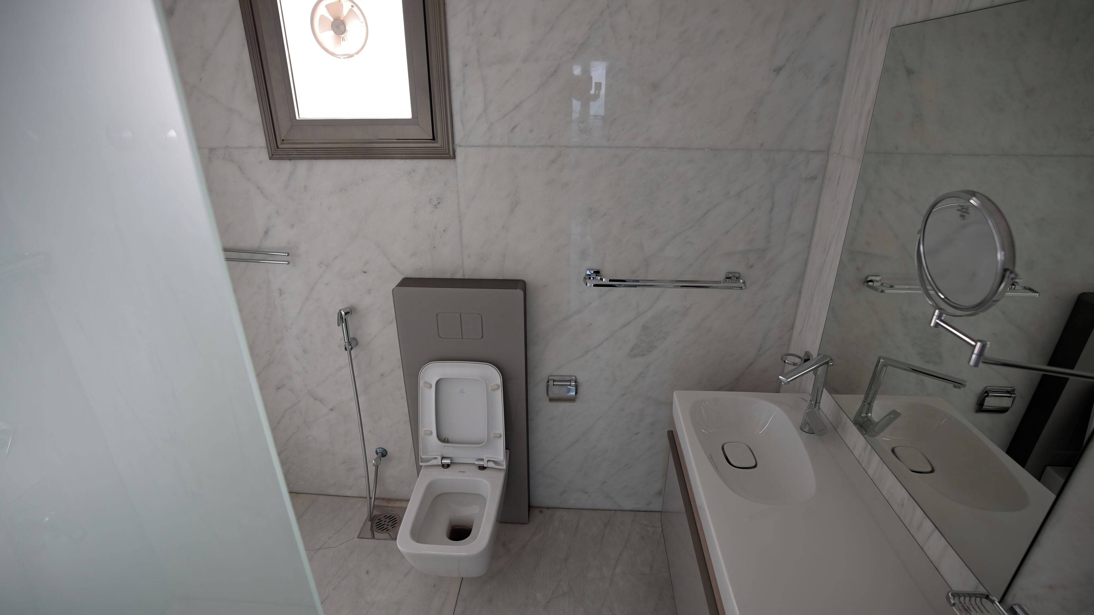Un baño moderno con inodoro, bidé y lavamanos con espejo.