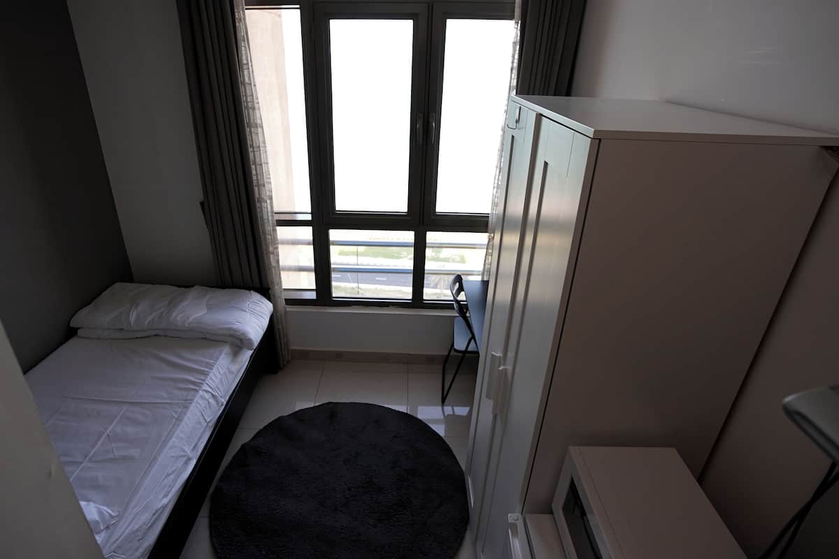 Une petite pièce, peu meublée, comprenant un lit, un bureau, une chaise et une armoire.