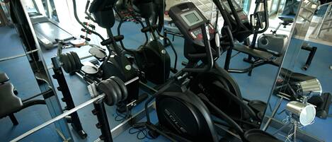 A gym with various exercise equipment including treadmills, elliptical machines, and weightlifting stations.