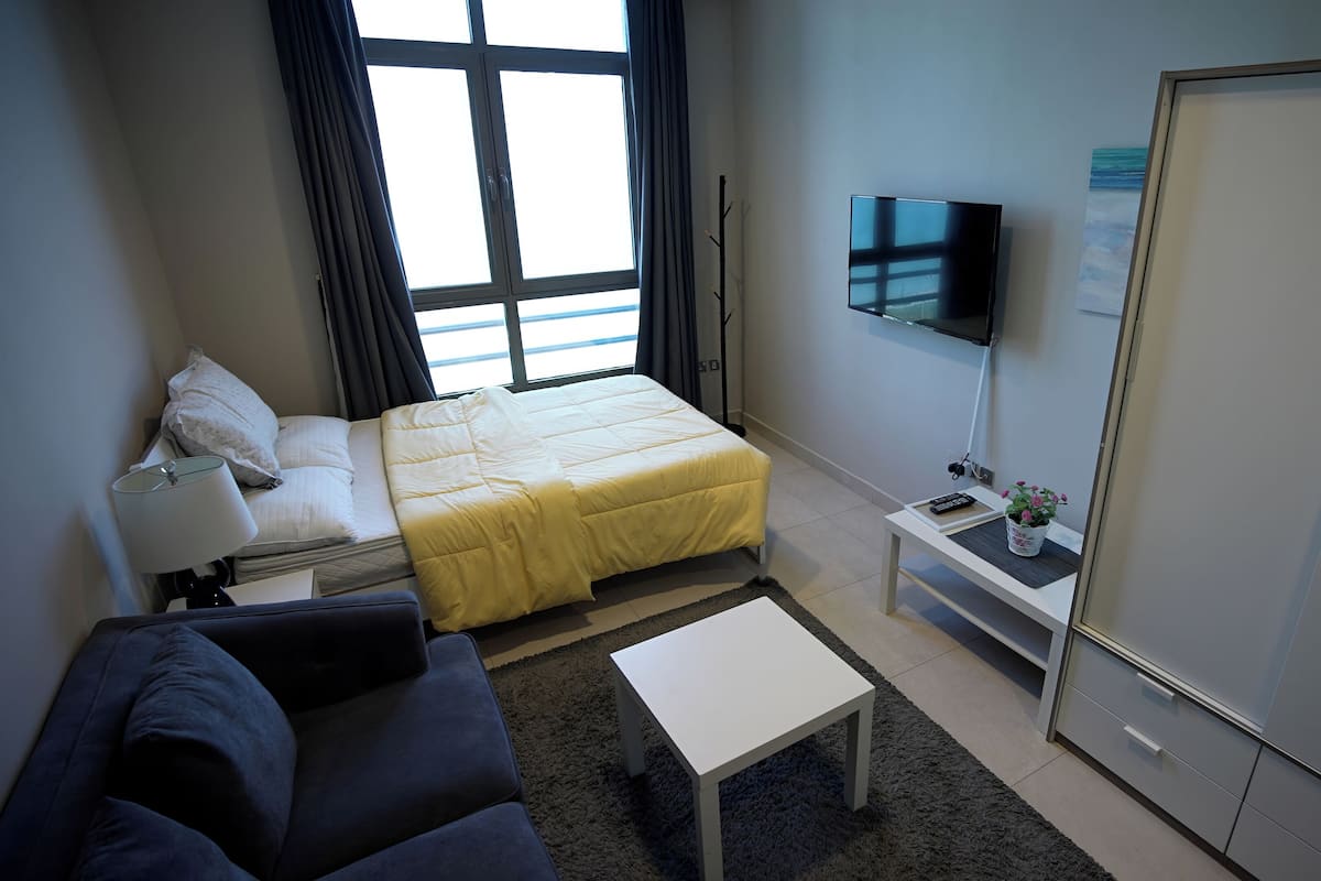 Une chambre d’hôtel équipée d’un lit, d’une télévision, d’un bureau, d’un canapé et d’une armoire.