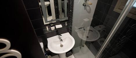 A modern bathroom with a white sink, a glass shower enclosure, and a separate toilet.