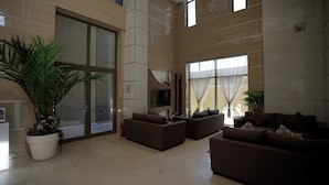 A spacious living area with large windows, a flat-screen TV, and multiple sofas.