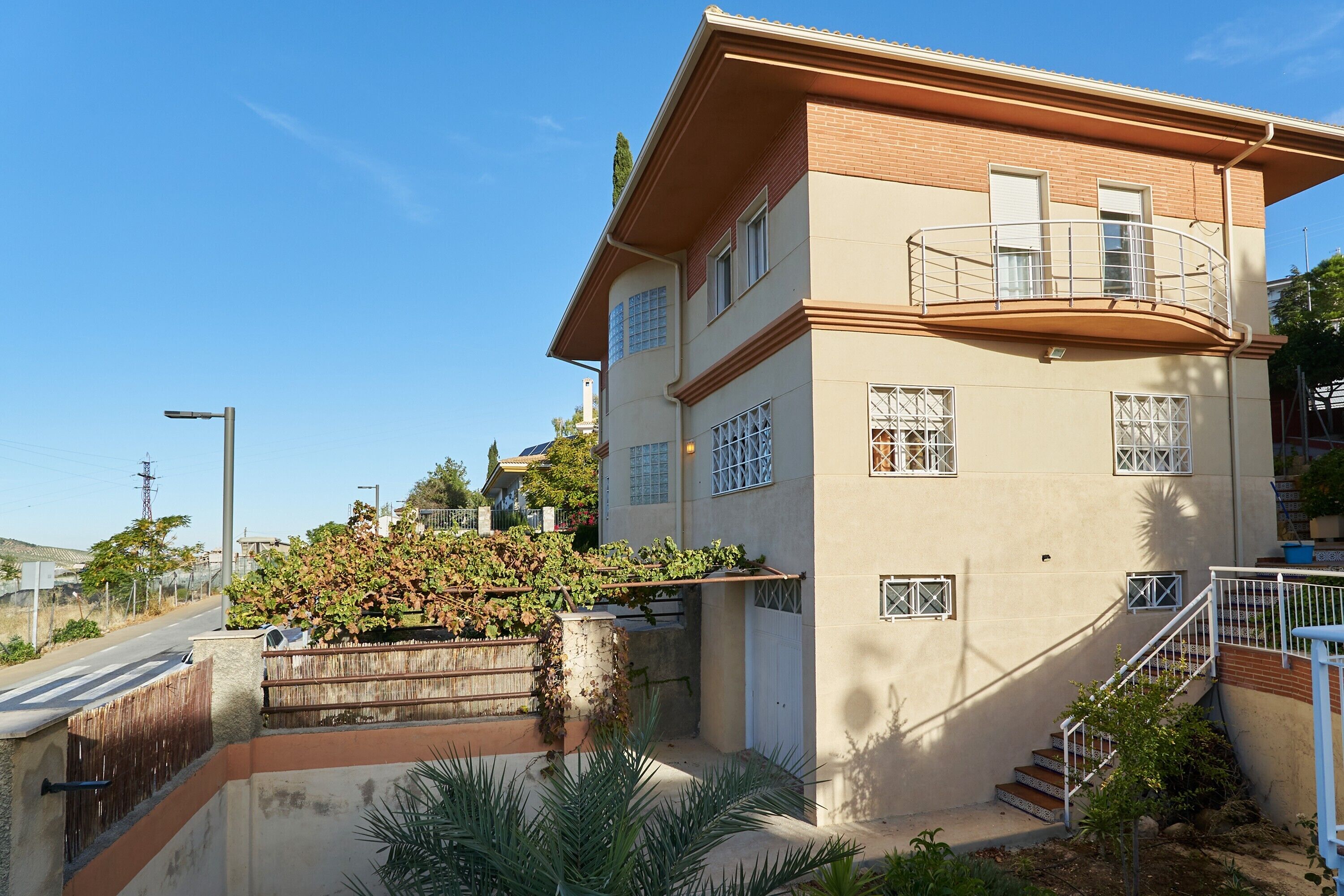A two-story building with a balcony, a staircase, and a small garden area.