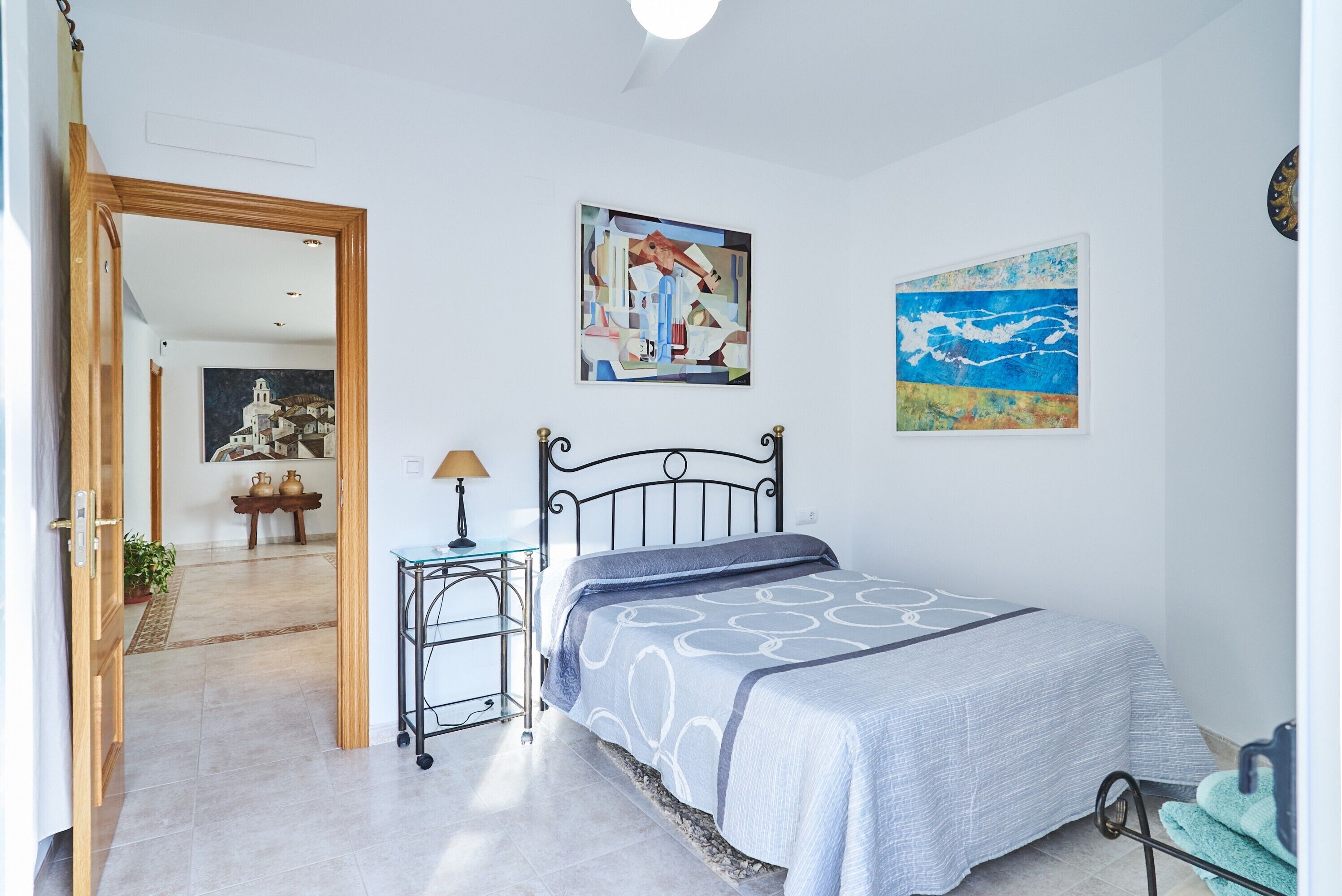 Une chambre à coucher avec un lit, une table de chevet, une lampe et deux tableaux accrochés au mur.