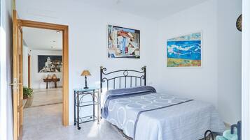 Une chambre à coucher avec un lit, une table de chevet, une lampe et deux tableaux accrochés au mur.