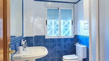 Une salle de bain avec un lavabo blanc, des toilettes et une fenêtre en verre dépoli.