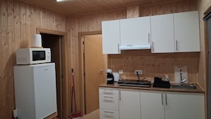 Eine kleine Küche mit Holzwänden, einer Mikrowelle, einem Kühlschrank, einer Spüle und Schränken.