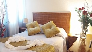 Un lit bien fait, agrémenté d’une serviette décorative, de deux oreillers et d’une tête de lit.