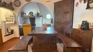A rustic kitchen with a large wooden table, a built-in oven, and a hanging light fixture. - Casa Bungavilia - Roots of Alentejo (Alvito)