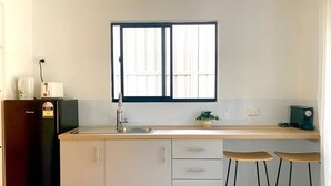 A kitchen with a window, a refrigerator, a sink, and two stools. - PP Garden (Bondi)