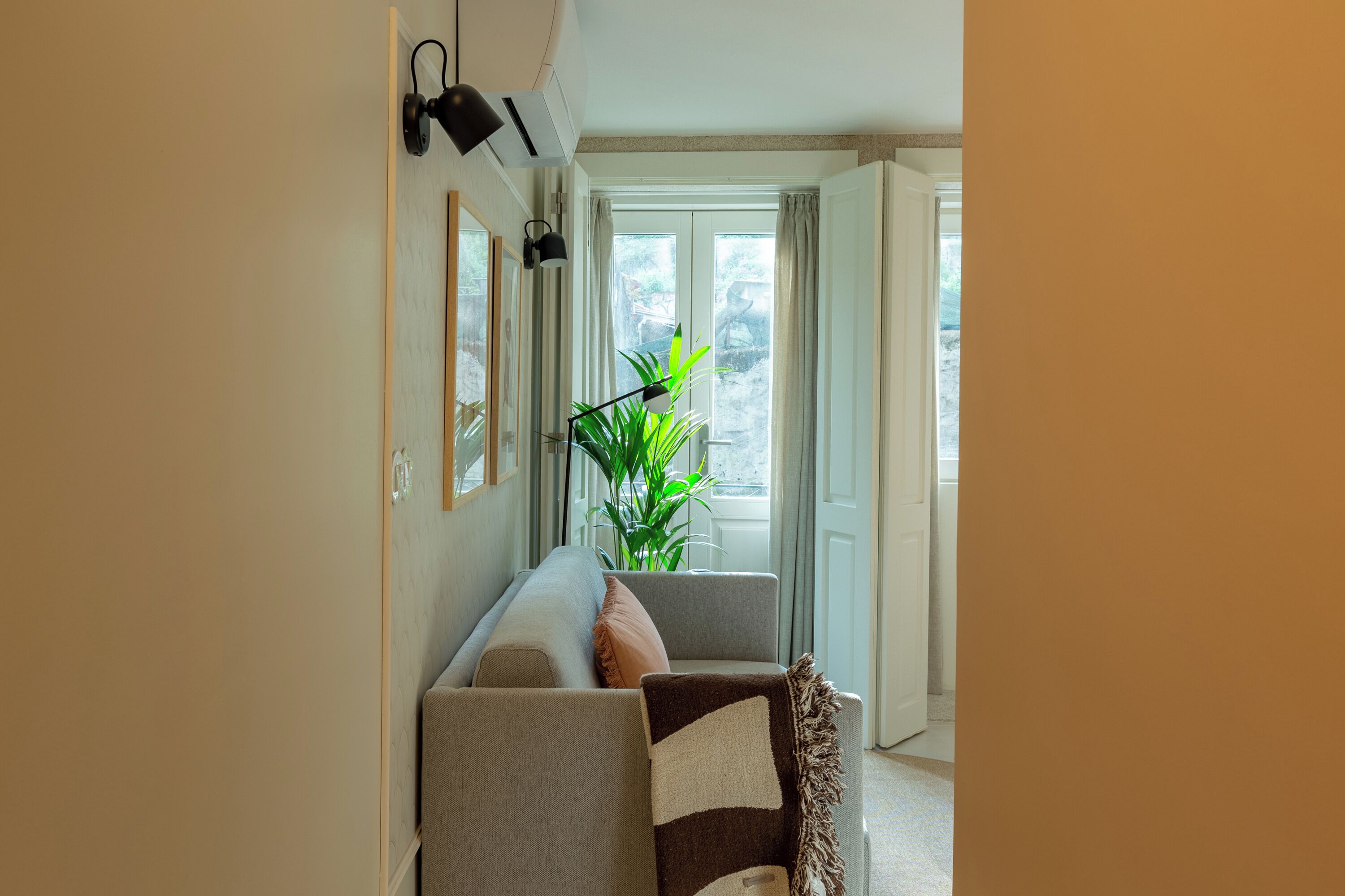 En hall med en soffa, en krukväxt och en dörr som leder ut till ett utomhusområde.