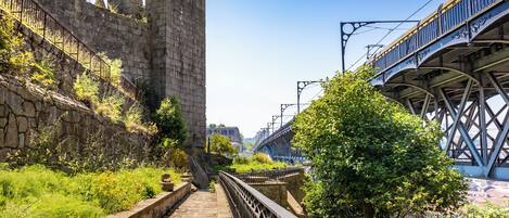 Un sentier de pierres mène à un château historique, avec un pont et des voies ferrées à proximité.