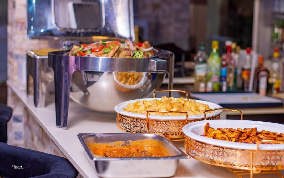 A buffet setup with various dishes, including a large pot of stew, bowls of potatoes, and a tray of what appears to be a casserole.